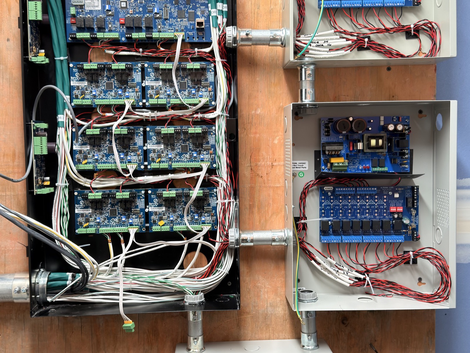 Access control panel with multiple door boards wired out to separate power supply enclosures on a plywood backboard